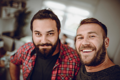 Deux amis hommes souriants se tenant debout et prenant une photo en mode selfie